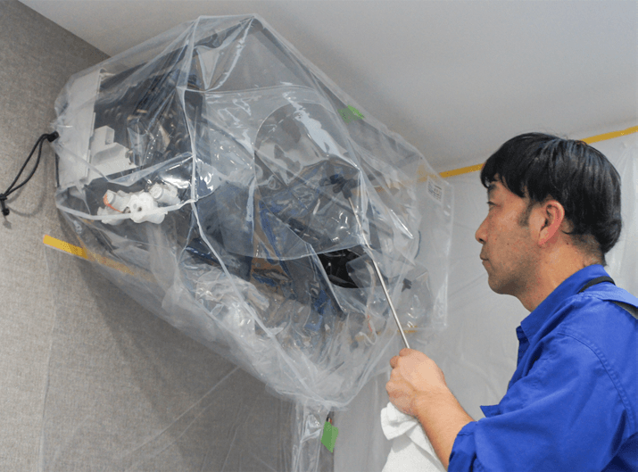 エアコンにカバーをして清掃している様子